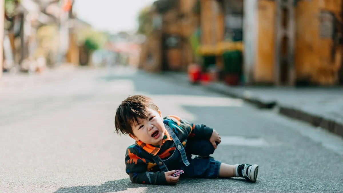 Jeune enfant en pleine crise de colère, parent à ses côtés
