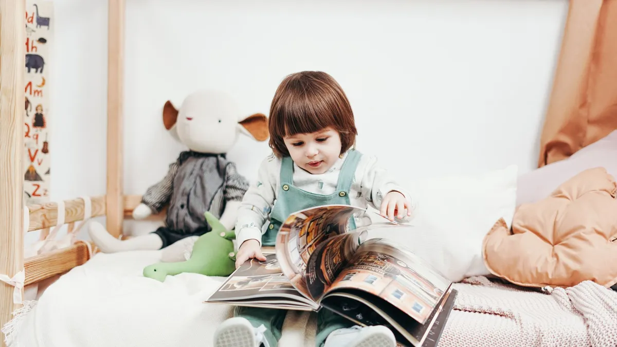 Enfant de 3 ans qui regarde un album illustré sur un tapis