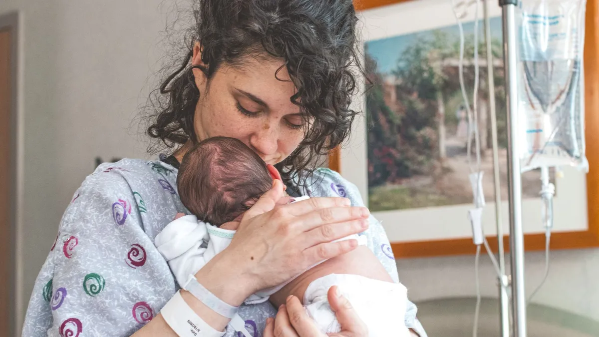 Jeune maman pensive tenant son nouveau-né dans ses bras
