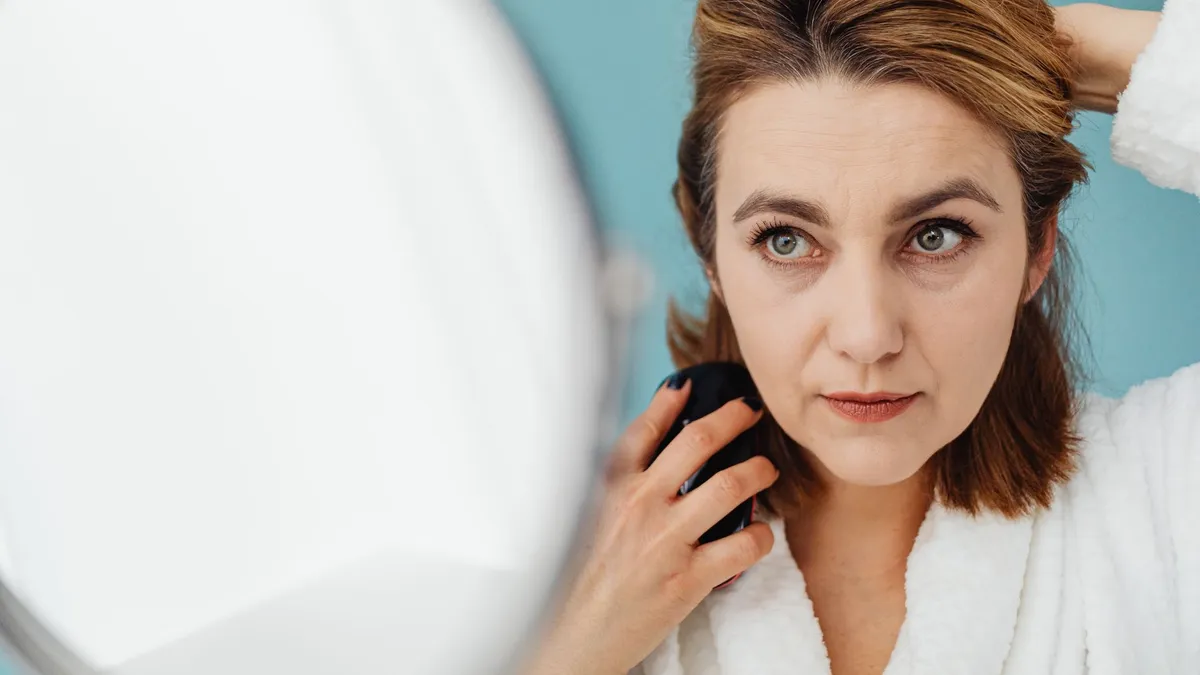 Jeune maman démêlant doucement ses cheveux devant un miroir