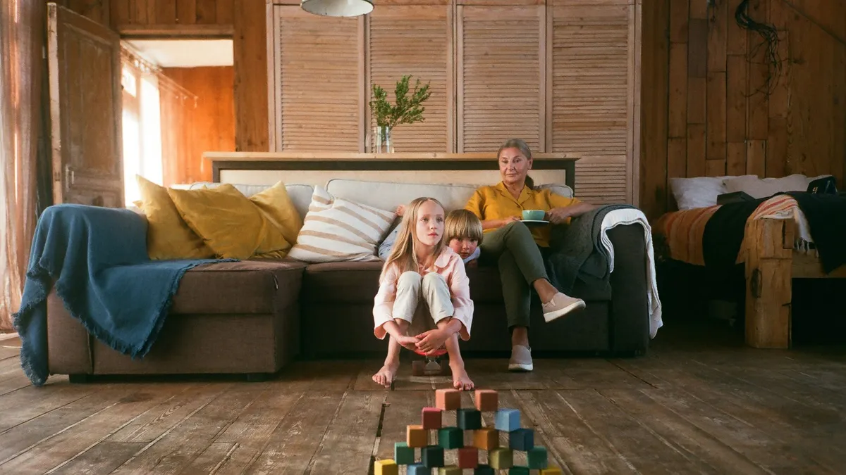 Parent épuisé assis, la tête entre les mains, dans un salon