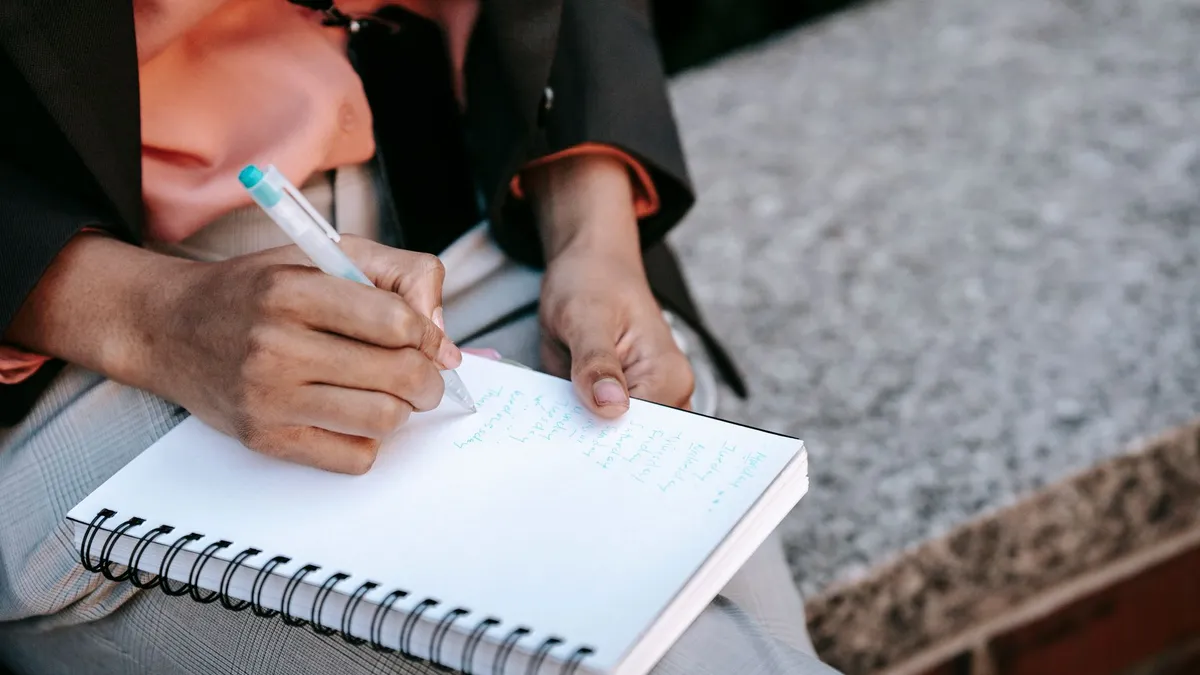 Future maman notant des idées de prénoms de fille dans un carnet