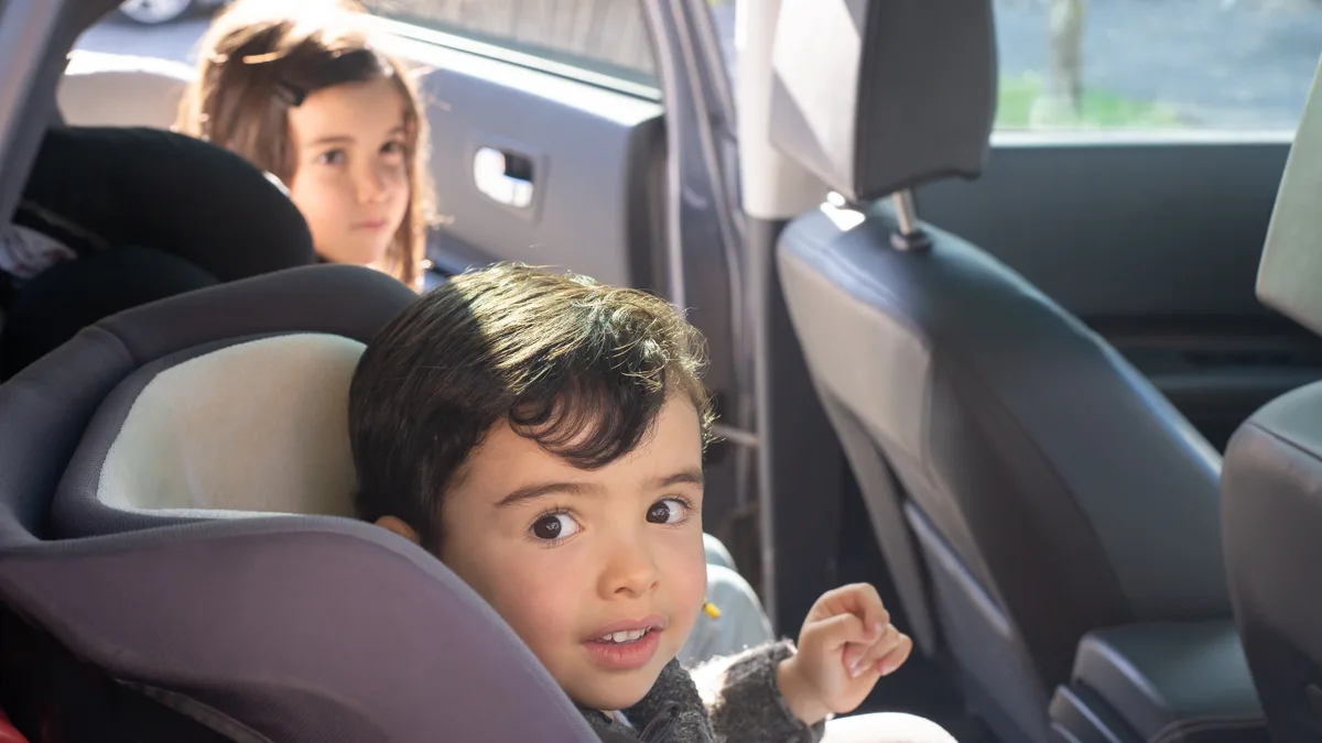 Deux jeunes enfants installés dans leurs sièges auto à l'arrière d'une voiture pendant un trajet