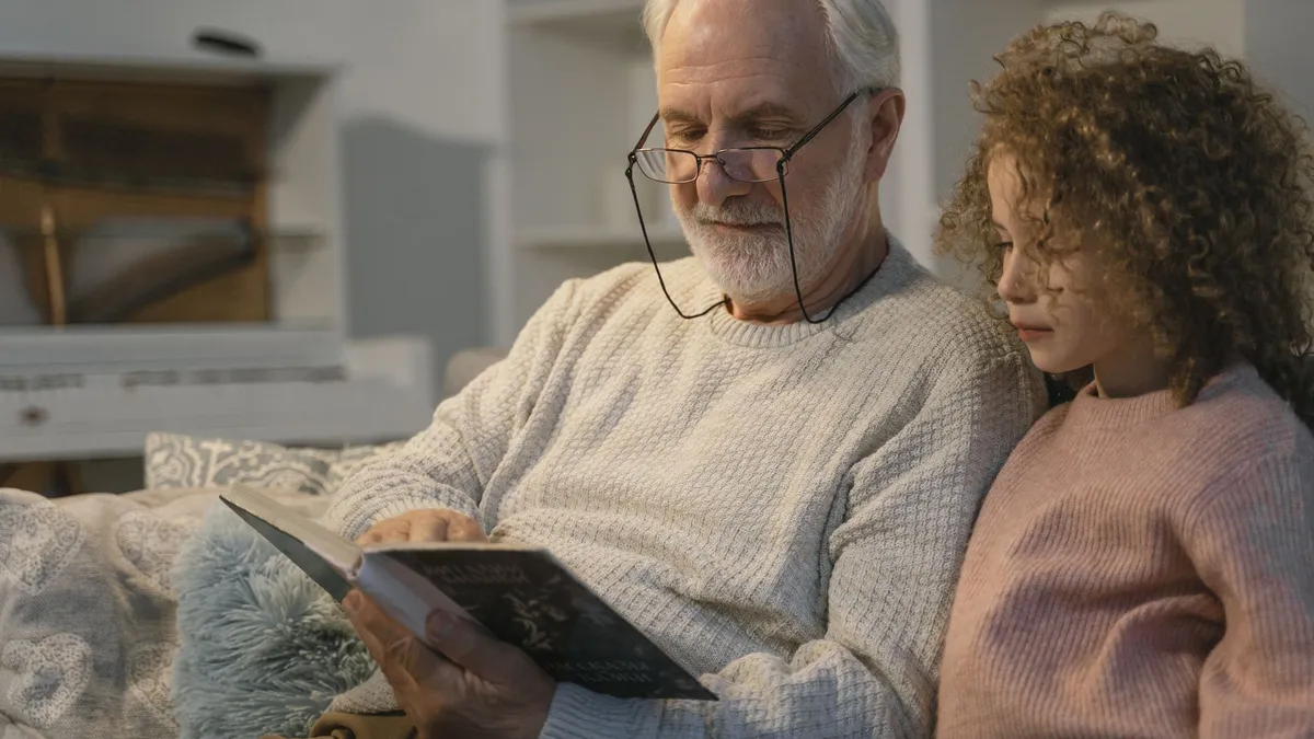 Un grand-père et sa petite-fille lisent un livre ensemble à la maison