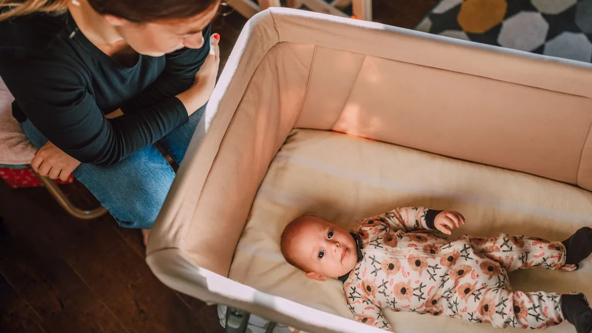 Un bébé dort paisiblement dans un berceau cododo accolé au lit des parents