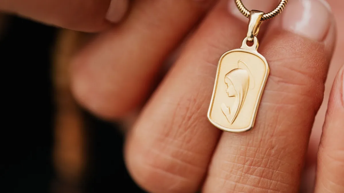 Médaille de baptême en or jaune posée sur un tissu clair